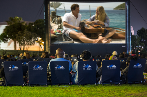 As the sun sets, moviegoers find the perfect spot to spread out their rented blankets or set up their low chairs on the lawn.