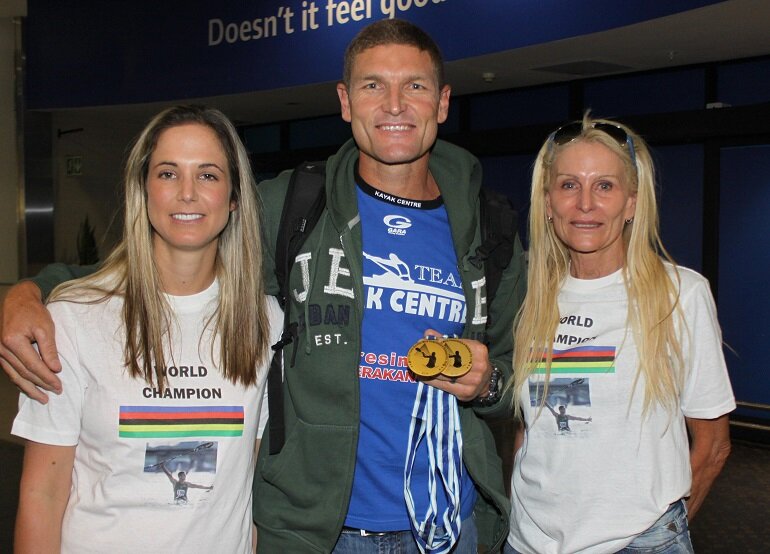 Hank McGregor (centre) is welcomed home by his wife Pippa (left) and mother Skyy McGregor at King Shaka International Airport on his return from the ICF Canoe Marathon World Championships.